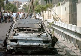 A burnt car is seen near the wall of the US Embassy compound in Damascus, which was the target of an attack on Tuesday.