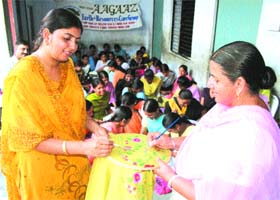 Ms Poonam gives tips on fabric painting to a woman at Mission Aagaaz camp