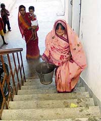 A BSNL Colony resident carries a bucket of water up the stairs