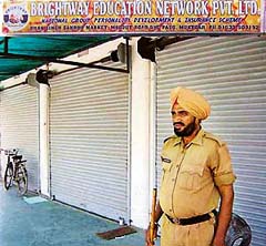 A policeman stands guard outside the office of the private firm that allegedly duped people of crores, in Muktsar