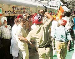 A policeman wields a lathi on BJP workers at the railway station in Amritsar