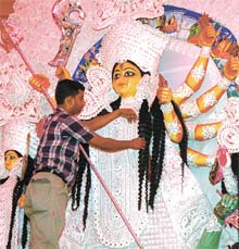 Last minute sprucing of a clay idol of Goddess Durga keeps an artist busy even as devotees got ready to start the Puja.