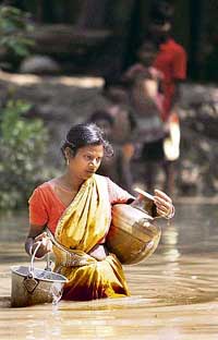 A woman carries drinking water through floodwaters at Udaynarayanpur village near Kolkata on Thursday. 