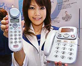 A Sanyo employee displays a cordless telephone handset with a bone-conduction speaker, "TEL-KU2"