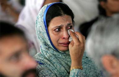 An unidentified woman wipes tears during a memorial ceremony on Sunday at Margalla apartment towers which collapsed in the October 8, 2005, earthquake, in Islamabad