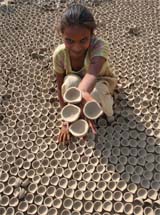 A potter girl shows earthen lamps before putting them in a furnace in Amritsar.