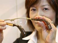 An employee of US hearing instruments giant Starkey's Japanese subsidiary displays a pair of glasses equipped with a new digital acouphone which has bone-conduction speakers enabling the user to listen to clear sounds vibrated through the skull of the user, at the annual International Optical Fair in Tokyo on Wednesday. The device is priced at $3,600 for a pair of glasses and $1,900 for the one-side acouphone model.