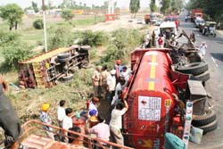 Employees of Indian Oil Corporation unload oil from a tanker that overturned after a head-on collision with a truck at Subhanpur on the Jalandhar-Amritsar National Highway 1