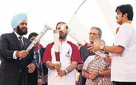 Qatar Prince Sheikh Joaan Bin Hamad K. H. Al Thani (right), Indian Olympic Association president Suresh Kalmadi and Indian Olympic Association secretary Randhir Singh (left) marry the Doha Asian Games flame in New Delhi