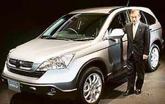Japan's Honda Motor Co. President Takeo Fukui stands next to the all-new version of its CR-V sports utility vehicle at a press preview in Tokyo