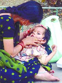 A woman trying to comfort her child, suspected of suffering from dengue, outside All India Institute of Medical Sciences (AIIMS) while awaiting her turn to consult with doctors