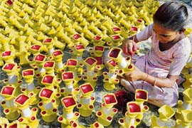 A girl child labourer gives final touches to earthern lamps at a workshop in Amritsar on Thursday.