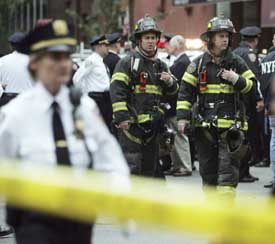 Rescue workers gather on York Avenue near the scene of a crash of a small plane into the Belaire Condo high-rise building in New York City on Wednesday