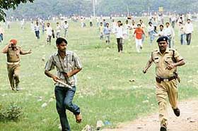 Jobless youth chase a policeman after violence broke out in Patna during the filing of applications under the National Rural Job Guarantee Scheme on Sunday.