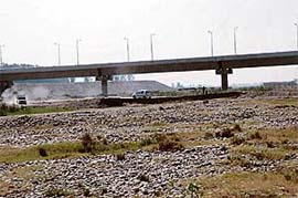 Vehicles use unsafe temporary bridge across the Ravi as Kathlore bridge awaits a VIP for inauguration.
