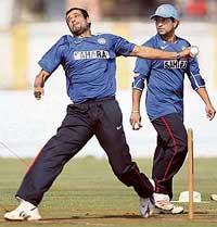 Irfan Pathan bowls as Sachin Tendulkar looks on during a practice session in Ahmedabad