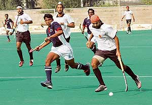 Prabhjot Singh (right) of Indian Oil Corporation takes the ball past a Tamil Nadu player during a super league match of the 62nd National Hockey Championship at the Olympian Surjit Hockey Stadium in Jalandhar on Saturday.