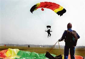 A colourful canopy makes a sharp contrast against a hazy sky as a paratrooper sails through air during exercise Chakravyuh in Sarsawa