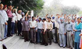 Postal employees hold a demonstration at the divisional headquarters near Bharat Nagar Chowk in Ludhiana on Tuesday