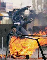 Palestinian demonstrators throw stones at Israeli soldiers in the West Bank city of Hebron during a protest against Israeli army shel