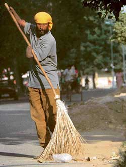 A physically disabled man, an employee of the Chandigarh Municipal Corporation, is sweeping road with a broom in Sector 7