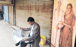 A man reading a newspaper during bandh at Karol Bagh in the Capital on Friday. 