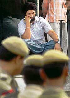 With despondency writ large on his face, a shopkeeper sits outside his sealed shop in a market in Delhi on Friday
