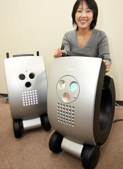 A woman poses with half-scaled models of Toshiba's prototype of a scooter-like tricycle for commuters, which can communicate with other vehicles using their LED headlights that flash several million times a second, at the company's headquarters in Tokyo