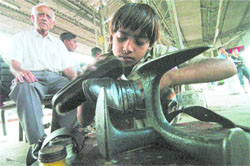 A child polishes shoes at the Amritsar railway station on the eve of Childrens Day