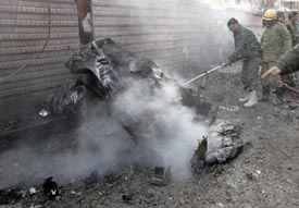 Firefighters try to extinguish the smouldering wreckage of a car used in a blast outside a security camp in Srinagar on Tuesday