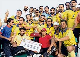 Punjab and Sind Bank players pose with the trophy after winning the 23rd Indian Oil Surjit Hockey Tournament in Jalandhar