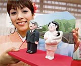 A girl displays Japanese traditional dolls called 'kawaribina' or newsmakers dolls for this year, featuring dolls of Japan's new Prime Minister Shinzo Abe (left) and the first lady Akie, at a press preview at the Mataro Doll Craft's showroom in Tokyo on Friday.