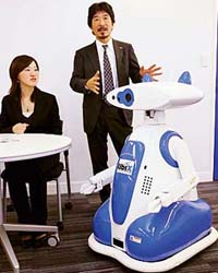 Japanese robot maker Tmsuk President Yoichi Takamoto introduces the robot "Ubiko", which can recognise human voice and speaks to guests as a guide or receptionist, at a press preview in Tokyo