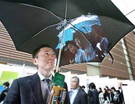 Japan's Keio University doctoral student Takashi Matsumoto displays the prototype model of the image or net browsing umbrella Pileus to make rainy days fun and to get information under the umbrella, at the university's advanced technology exhibition in Tokyo on Thursday. 