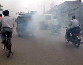 An auto rickshaw emits thick black smoke while traffic police turns a blind eye