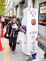 A customer wearing costume, depicting a controller of Nintendo's new video game console "Wii", queues outside at a Tokyo electric shop