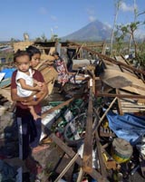A girl carries her cousin as her mother salvages items from their house destroyed by typhoon Durian in Daraga town in Philippines on Saturday
