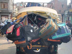 Having packed schoolchildren (inside) and their bags (outside) an autorickshaw driver theads his way to a school in Amritsar