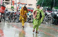 Two women rush to save themselves from the drizzle that continued throughout the day in Ludhiana