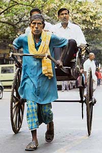 A rickshaw-puller pulls his passengers on a road in Kolkata