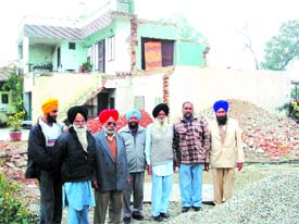 Tanda residents who have not been paid compensation for their houses and lands by the NHAI stand in front of the broken house of Ujjal Singh