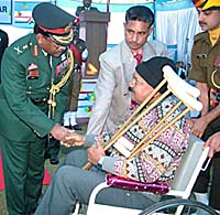 Lt Gen Noble Thamburaj, General Officer Commanding, Vajra Corps, intrects with Petty Officer Harbans Lal (retd) after presenting him with a wheel-chair during an Army Flag Day function in Jalandhar on Thursday.