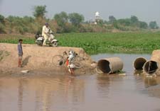A cyclist faces difficulty in crossing the Jassowal drain while a scooterist awaits his turn