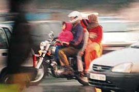 A family rides on a motor cycle on a cold evening in Chandigarh