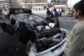 Iraqi children inspect the wreckage of a car at the site where a suicide bomber detonated a pickup truck packed with explosives among a crowd of casual labourers in downtown Baghdad on Tuesday