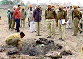 A police party exhumes the body of Darshan Singh, a resident of Banur who was murdered and buried in a dried-up pond
