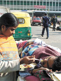 A patient being spoonfed by a well-wisher outside AIIMS