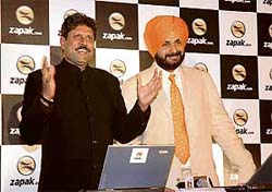 Former Indian cricketers Kapil Dev and Navjot Singh Sidhu play an online cricket game at its launch in New Delhi on Tuesday. 