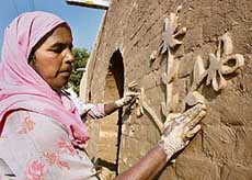 A woman gives finishing touches to Jaipalgarh, a heritage village, being built for Virasat mela, in Bathinda on Tuesday. 
