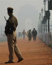 A security guard keeping a vigil during the early morning fog which enveloped the Capital on Wednesday, casting an eerie spell over the India Gate as tourists throng the area.